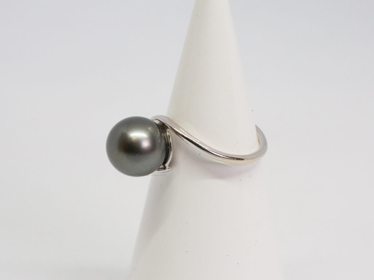 Modern Tahitian black pearl and white gold ring. Elegant and aesthetically pleasing ring in 18 karat white gold with large natural Tahitian black pearl. Comes with small ring box. Ring size N / 6.5 Ring weight 4gms. Photo of ring displayed on a cone shaped stand and shown with pearl to the left.