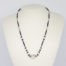 Vintage Art Deco crystal glass necklace. Subtly sparkly handmade clear and navy crystal bead necklace linked with brass throughout. c1930. Clasp not original. Main photo of necklace displayed on a stand seen face on.