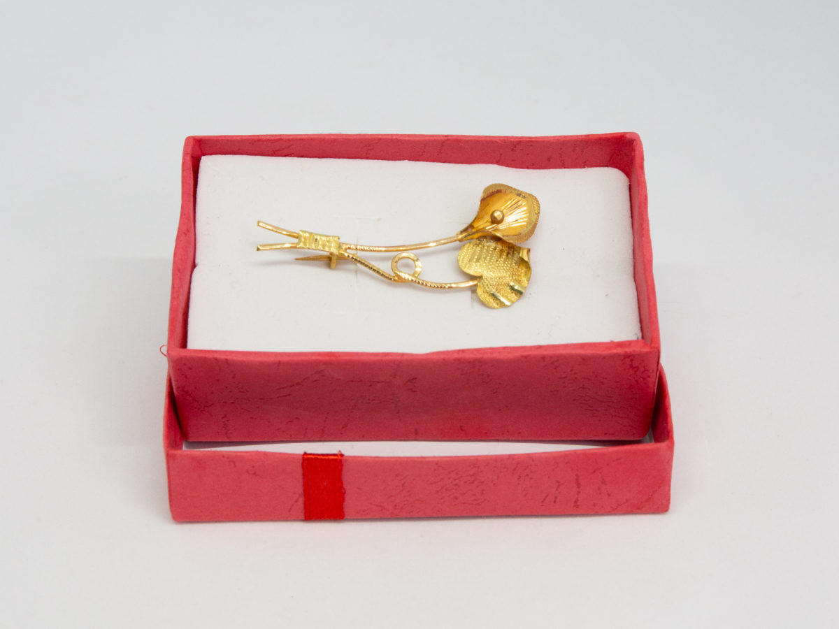 20 karat gold peace lily brooch. Modern brooch in 20 karat gold of a peace lily flower and leaf. Hallmarked XXct (for 20carat) to the base of one stem. Brooch measures approximately 48mm long and weighs 3.5gms. Box included. Photo of brooch displayed in a red card box.