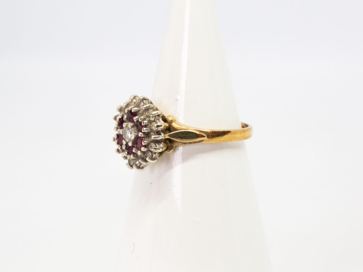 Vintage 9 karat gold ring. Pretty ring with a floral front of rubies and diamonds. Full hallmark to inside band for Birmingham assay c1987 Ring size L / 5.5. Photo of ring on a cone shaped display stand with ring front facing left.