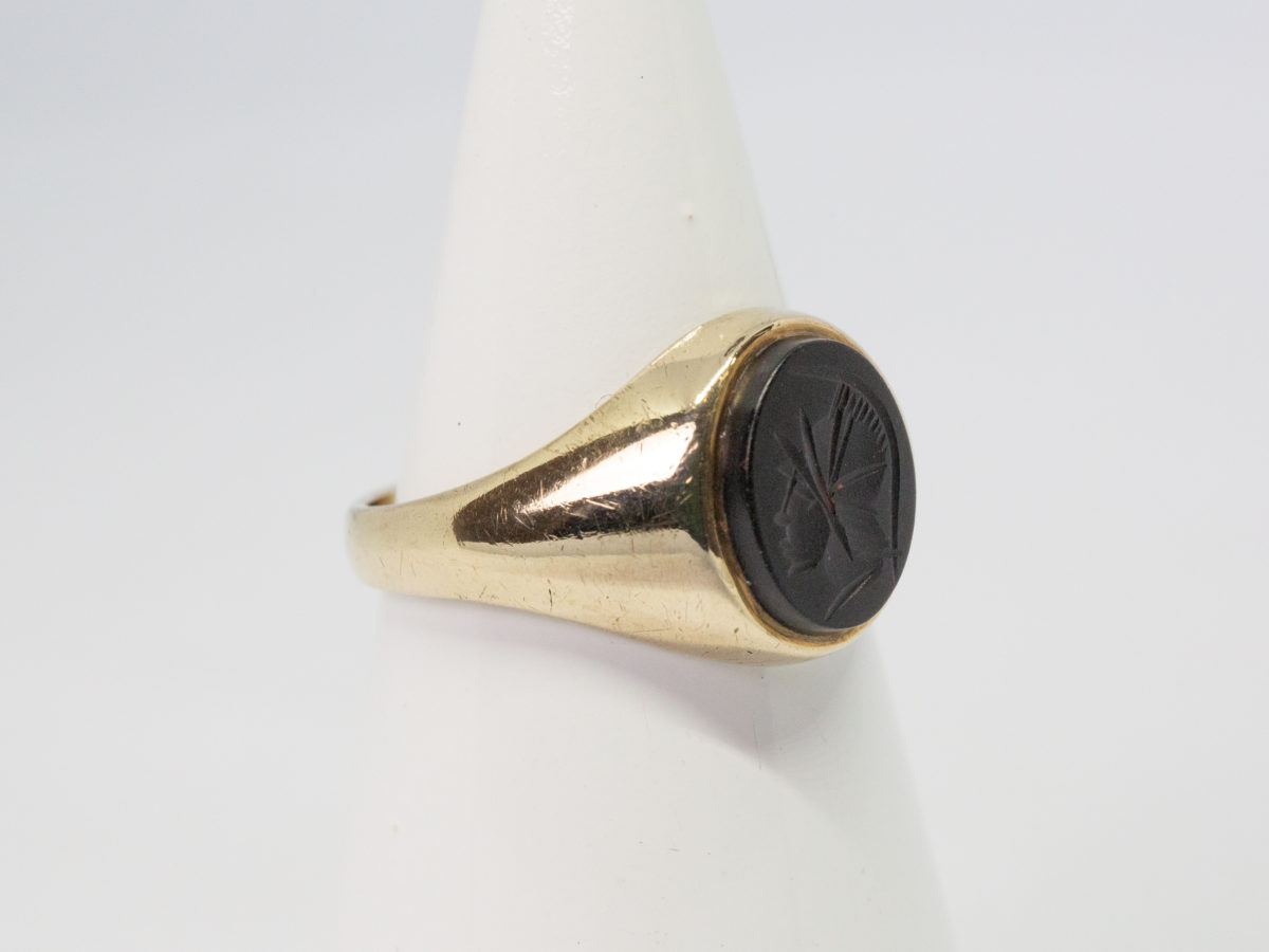 Vintage 9 karat gold and hematite ring. c1978 Birmingham assayed 9 karat gold ring set with a hematite intaglio showing profile of a Roman soldier. Ring size T.5 / 9.75 Photo of ring on a cone display stand and seen with ring front facing right of photo.