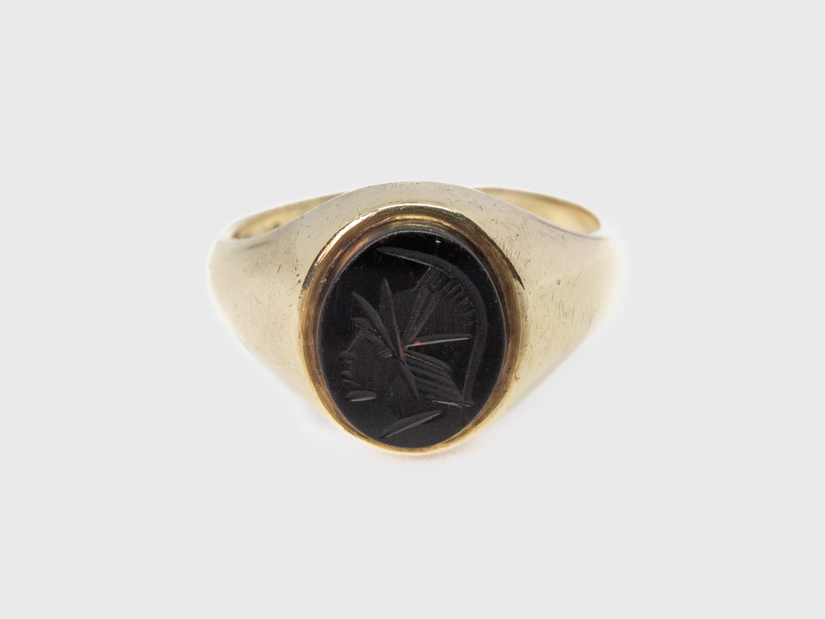 Vintage 9 karat gold and hematite ring. c1978 Birmingham assayed 9 karat gold ring set with a hematite intaglio showing profile of a Roman soldier. Ring size T.5 / 9.75 Photo of ring on a flat surface and shown front facing.