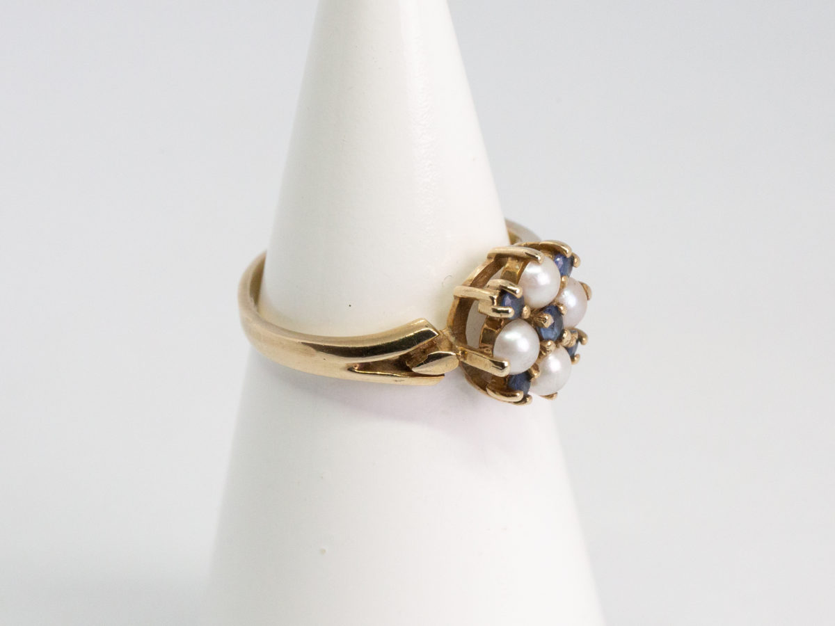 Vintage 9 karat gold, sapphire and pearl ring. Pretty 9 karat gold ring set with 5 small round cut blue sapphires and seed pearls. Hallmarked for Continental import with Birmingham assay. Ring size Q / 8. Ring weight 3.2gms. Photo of ring on a cone shaped stand and seen with ring front facing right.