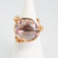 18 karat rose gold and amethyst ring. A stunning statement ring in 18 karat rose gold with a large faceted round cut lilac amethyst stone. Unusual raised setting with 3 hoop claws to secure the stone. Looks incredible worn! Italian made quality design. Hallmarked to the inside band. Ring size M / 6. Weight 12.7gms. Main photo of ring displayed on a cone shaped stand with ring front facing forward.