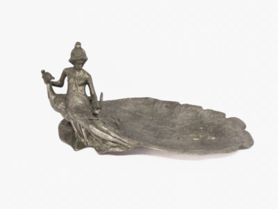 Antique Art Nouveau pewter pin tray. A rare and very lovely decorative pewter pin tray of a young lady seated on the back of a peacock gazing into a mirror. The tray area is plumes of the peacocks fanned out feathers. Lots of attention to detail in this piece. Is she looking at herself or the peacock in the mirror? 95% pewter (Zinn 95%) Main photo showing pin tray from side angle showing the full length of the peacocks tail