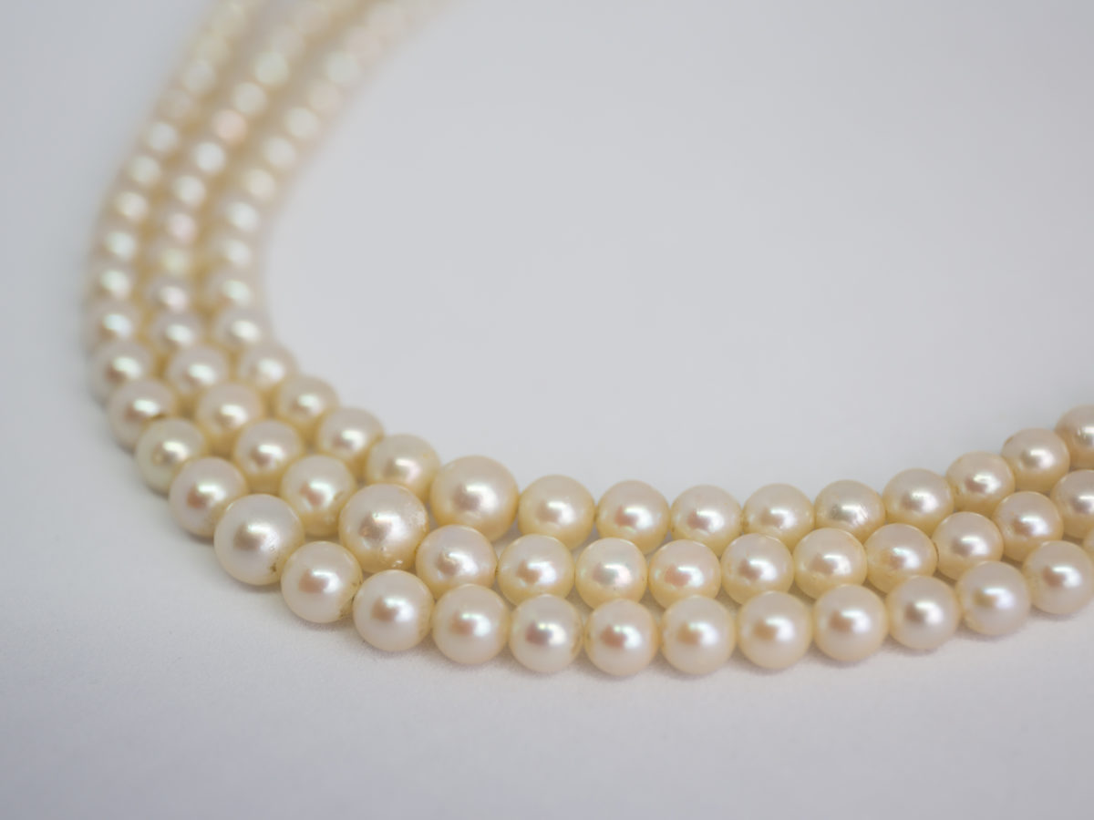 Art Deco graduated pearl necklace. Stunning necklace with 3 strands of graduated pearls and a paste stone encrusted clasp. Unidentifiable hallmark to back of clasp. Made in France. Shell shaped box included but not original. Shortest strand measures approximately 420mm and longest 450mm. Necklace weight 47gms. Close up photo of the front of all 3 strands of pearls.