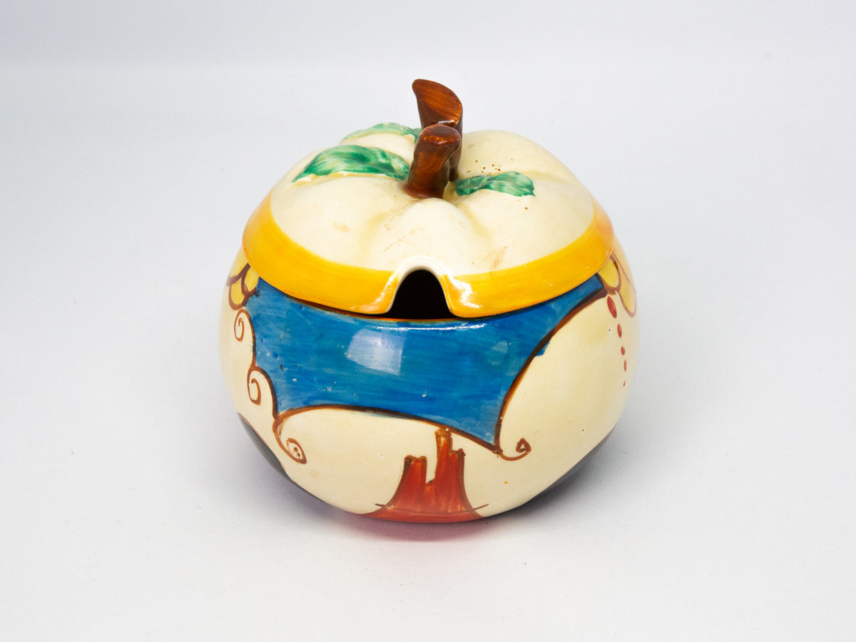 Apple shaped preserve pot by Clarice Cliff. A fun, funky hand-painted preserve pot in the Fantasque Bizarre line, 'Summerhouse' pattern. In excellent condition. Signed to the base. c1931-1933. Measures 50mm in diameter at base, 95mm at bulbous middle and approximately 85mm at tallest. Main photo of pot with spoon hole showing at the centre and the blue bit of pattern in foreground.