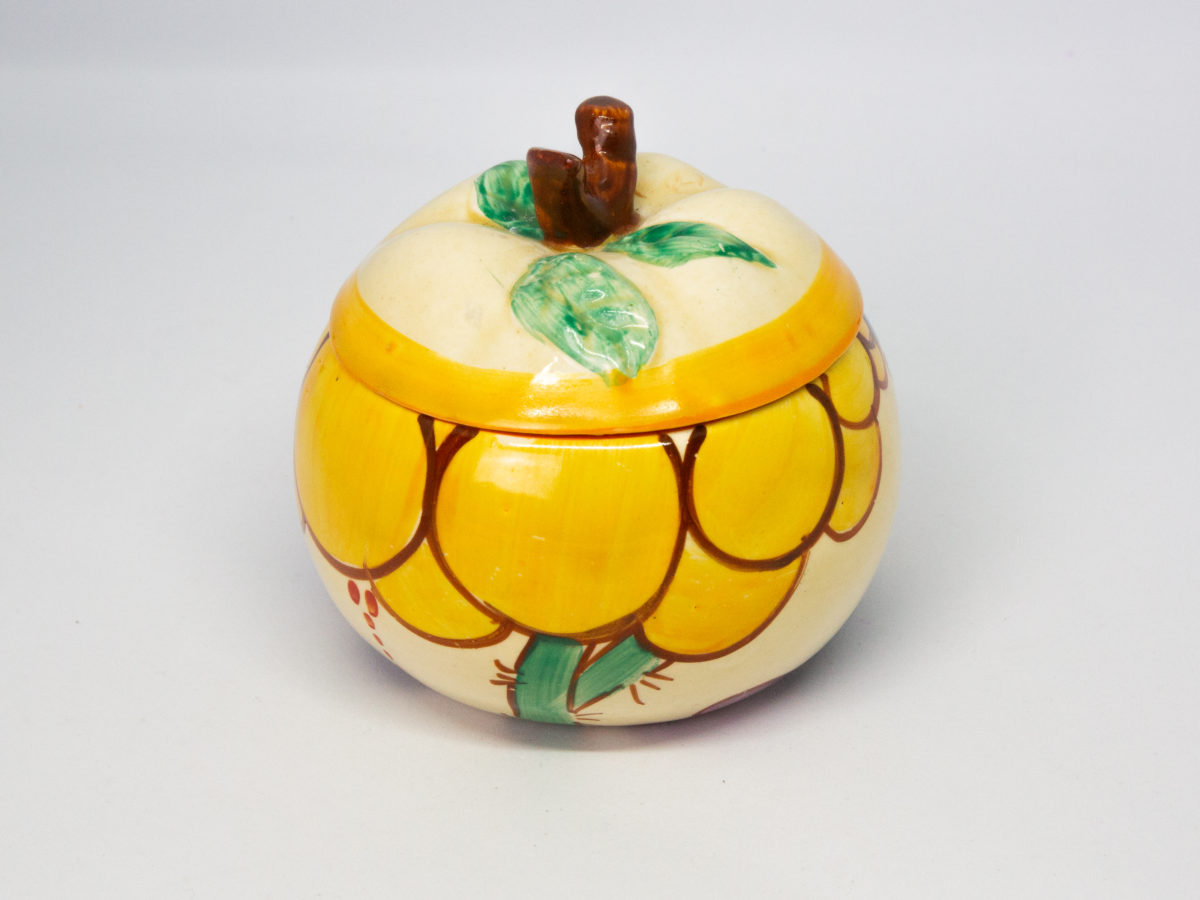 Apple shaped preserve pot by Clarice Cliff. A fun, funky hand-painted preserve pot in the Fantasque Bizarre line, 'Summerhouse' pattern. In excellent condition. Signed to the base. c1931-1933. Measures 50mm in diameter at base, 95mm at bulbous middle and approximately 85mm at tallest. Photo of pot with just the yellow bubble pattern showing.