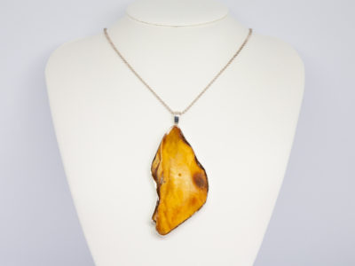 Rare large egg yolk amber pendant and chain. Stunning huge egg yolk amber set in a sterling silver frame on a sterling silver ball chain. Hallmarked to the pendant bail for London assay c1997 and 925 on the chain clasp. Pendant drop length 95mm and 45mm at widest. Main photo of necklace displayed on a stand and looking straight on.