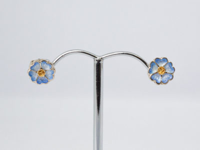 Vintage Sheila Fleet enamelled silver earrings. A sweet pair of sterling silver stud earrings in a flower shape with blue enamel to the petals by Sheila Fleet, Orkney Islands. Hallmarked 925 on stud post and butterfly. Original Sheila Fleet box included. Flowers measure approximately 8mm in diameter and weigh 1.7gms. Main photo of earrings displayed on a stand shown front facing.