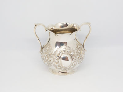 Antique 2 handled sterling silver pot. Small 2 handled sterling silver pot with intricate relief pattern around the lower bulbous area. One cartouche has a profile of a medieval knight engraved to it while other cartouche is empty - for a damsel perhaps? Shapely handles and rim add to the elegance of this piece. Full hallmark to the base for London assay c1875. Made by Francis Higgins. Base measures 55mm in diameter, width across handles measures approximately 105mm and opening at top 60mm in diameter. Main photo of pot seen from the side with empty cartouche and handles to either side.