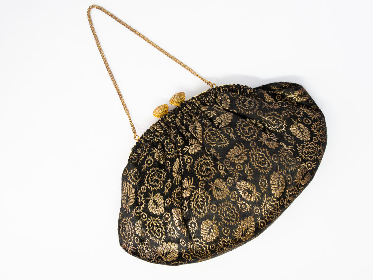 Vintage French black and gold evening bag. Small and pretty evening bag in black and gold with sparkly crystals to the clasp. Lovely cream satin interior with a small pocket housing a mirror. Some gilt wear to frame. Drop length from chain handle to bottom of bag is 235mm. Main photo of bag laid on a flat surface with gilt chain handle stretched out to top left corner and bottom of bag in bottom right.