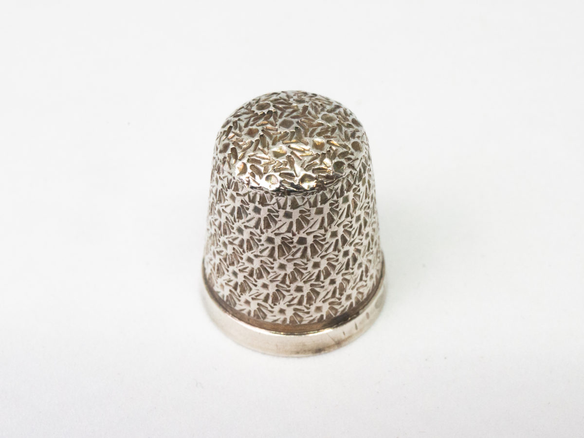Sterling silver thimble in a fitted velvet case. Lovely sterling silver thimble in a fitted red velvet case with clasp. Fully hallmarked to the side of the thimble for c1927 Birmingham assay. Considerable wear to the velvet case. Thimble measures 20mm long and 16mm in diameter at opening. Thimble weight 2gms. Photo of thimble on a flat surface looking from a slightly raised angle.