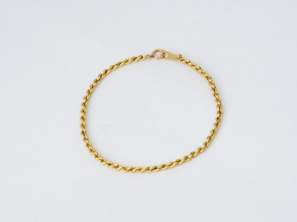 Vintage 18 karat gold rope chain bracelet. Fine rope chain bracelet in 18 karat yellow gold. Hallmarked 750 for 18 karat gold. Main photo of bracelet laid out in a circle on a flat surface with clasp done up.
