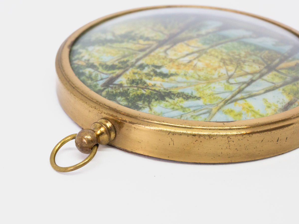 Hand-painted miniature with brass frame. Lovely hand-painted miniature of a man fishing by the river under the trees and a second person asleep. Wonderful detail to this piece of art. Measures 75mm in diameter. Drop length from top of bail measures 92mm. Close up photo of the ring bail area of picture frame.