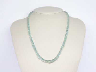 Modern aquamarine bead necklace. Pretty necklace made up entirely of graduating faceted aquamarine stones beautifully strung and finished with a sterling silver clasp. Main photo of necklace displayed on a stand and seen forward facing.