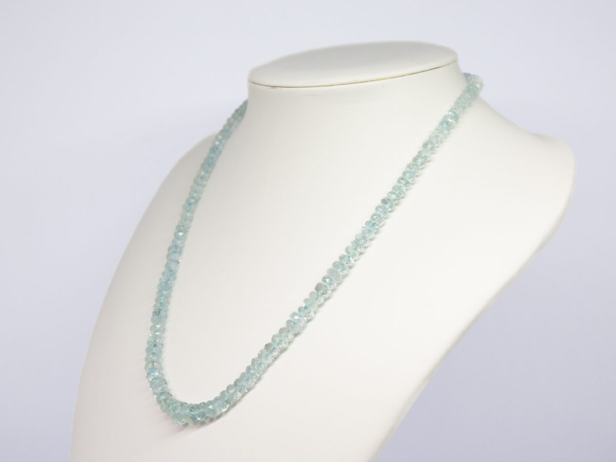 Modern aquamarine bead necklace. Pretty necklace made up entirely of graduating faceted aquamarine stones beautifully strung and finished with a sterling silver clasp. Photo of necklace on a display stand and seen from a slight side on angle.