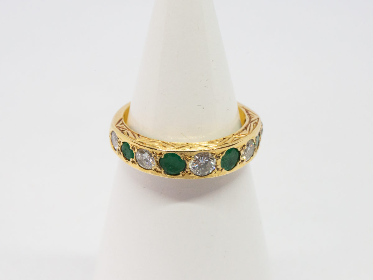 Vintage 18 karat gold ring with emeralds and diamonds. A stunning 18 karat gold ring set with 4 emeralds and 5 diamonds in an alternating row. Fully hallmarked for Sheffield assay c1975. Box included. Ring size O.5 / 7.25. Ring weight 3.8gms. Main photo of ring displayed on a cone shaped stand and seen forward facing.