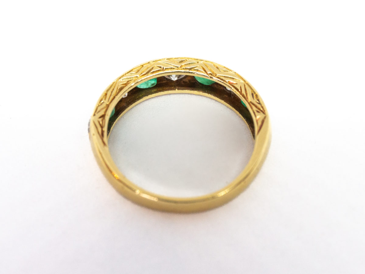 Vintage 18 karat gold ring with emeralds and diamonds. A stunning 18 karat gold ring set with 4 emeralds and 5 diamonds in an alternating row. Fully hallmarked for Sheffield assay c1975. Box included. Ring size O.5 / 7.25. Ring weight 3.8gms. Photo of ring on a flat surface and seen from a raised angle and ring front facing away from shot.