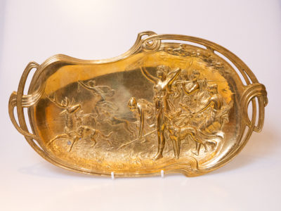 Antique Art Nouveau brass wall plaque or tray. A highly decorative brass wall plaque with a typically Art Nouveau look depicting a scene of the Goddess Diana on a hunt. There is a signature to the back which is hard to read but believed to be of French origin. Main photo of plaque displayed upright on a plate display stand showing full image of Goddess Diana on the hunt. It is said that the images of the females shown are all of the Goddess in different hunting poses.