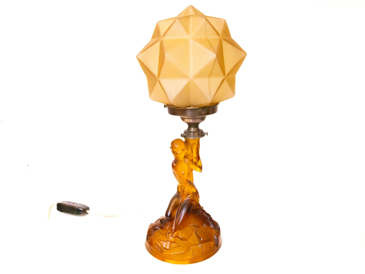 Art Deco glass lamp and shade. Stunning amber glass lamp of semi naked seated lady holding a multi dimensional amber glass shade. The shade is a slightly lighter colour to the main lamp. Lamp base measures 145mm in diameter. Photo of lamp from a slightly different angle