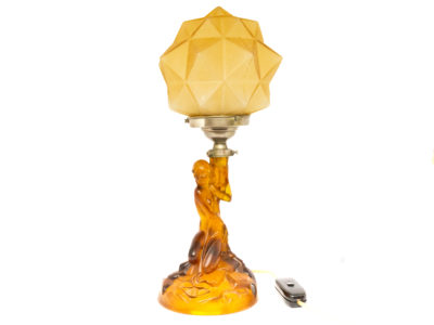 Art Deco glass lamp and shade. Stunning amber glass lamp of semi naked seated lady holding a multi dimensional amber glass shade. The shade is a slightly lighter colour to the main lamp. Lamp base measures 145mm in diameter. Main photo of lamp seen from an eye level angle.