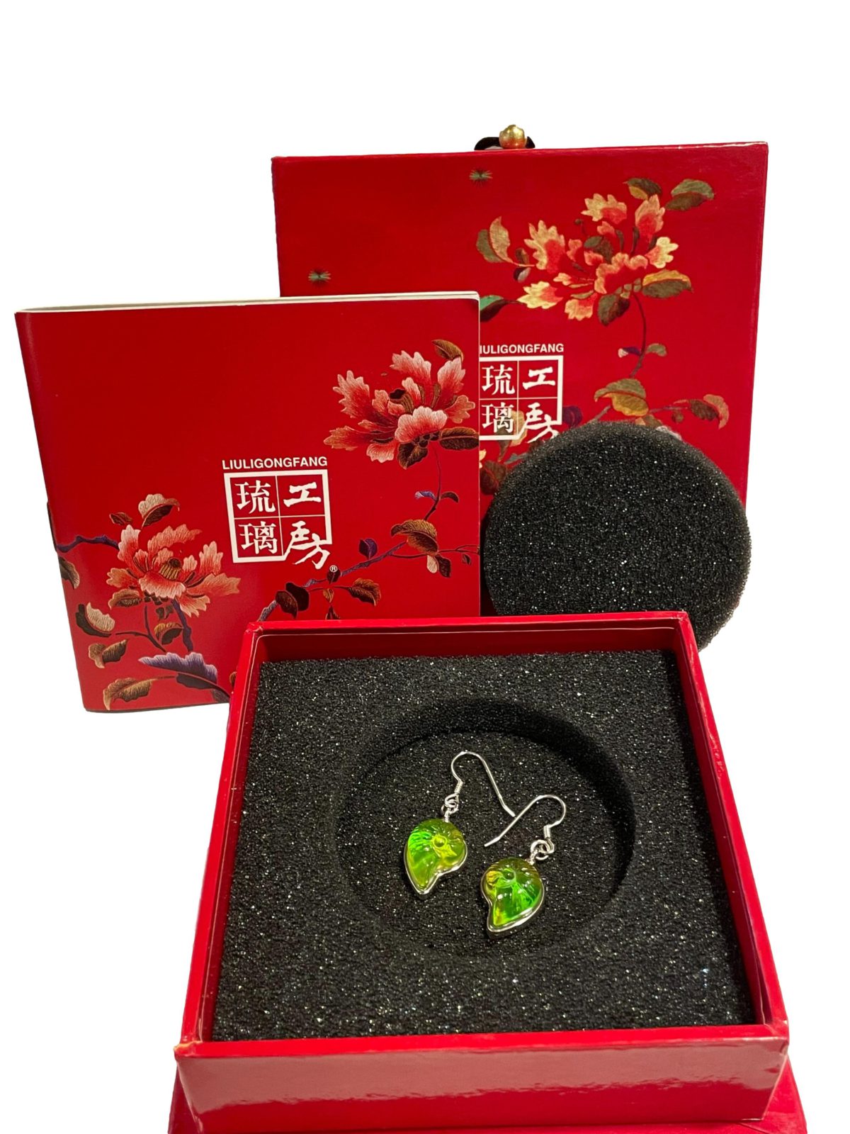 "Sound of the Ocean" earrings by Liuli Gong Fang. Made in sterling silver and green pâte-de-verre crystal in the form of a shell. Drop length approximately 40mm. Photo of earrings displayed inside the original box along with some leaflets with information about the process of making the crystal.