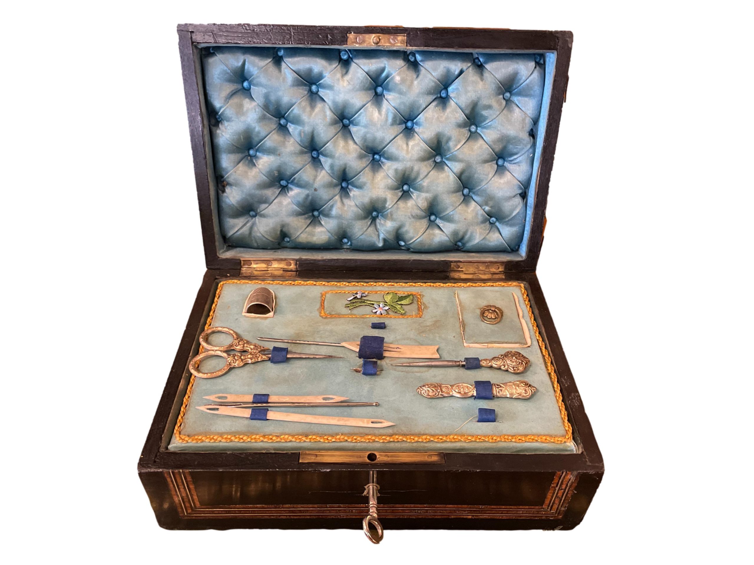 Napoleon Palais Royale sewing box with key and part original contents. Ebonised wood exterior with tulip wood veneer, brass inlay and cartouche. The inside is  lined with padded pale blue silk to the lid and base with removable tray housing the sewing tools. Napoleon III 1850-1899. Main photo showing box with lid open and tool tray in place.