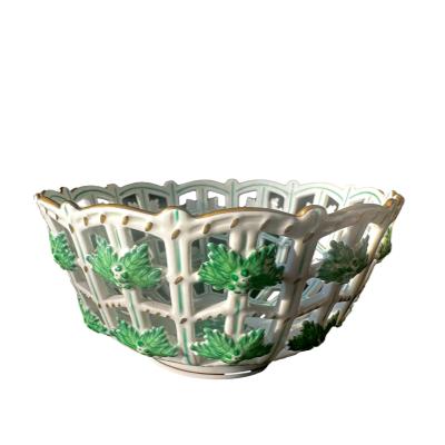 A vintage porcelain hand-painted bowl of lattice open work design by Herend of Hungary. Main photo looking at bowl from an eye level angle showing the lattice design and leaf decorations.