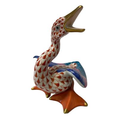 Herend porcelain honking goose figurine in red fish scale pattern. 24karat gold to beak & tips of webbed feet. Hand-painted and numbered to the base. Made in Hungary. Main photo of goose with front of body facing bottom left, open beak at top right and tip of tail feathers mid photo to the right.