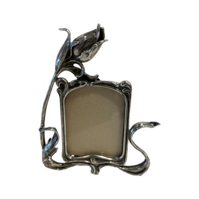 A small modern sterling silver photo frame in the Art Nouveau style. Pretty frame with a single tulip flower coming off to the left side of frame as if to embrace the photo. Hallmarked 925 for sterling silver to the back. Main photo showing frame from the front with the tulip flower to the left.