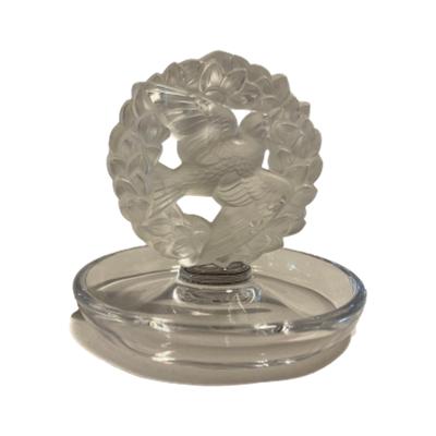 Modern Lalique frosted and clear glass ring tray with a dove of peace and wreath to the centre. Signed to the base. Tray measures approximately 100mm in diameter, central wreath area measures 75mm in diameter. Main photo of tray seen from an eye level angle dove is to the foreground of wreath and facing top right as if in flight.