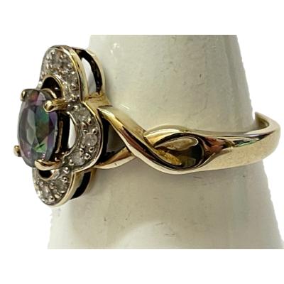 A 9ct gold Gypsy ring size M with a colourful Mystic stone and diamond setting. Photo of ring on a cone shaped stand with ring front facing left and the twist of the band on the shoulder visible.