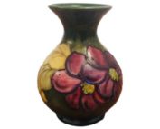 Moorcroft hibiscus vase with purple and red flowers on green. Paper label to the base W Moorcroft by appointment to the late Queen Mary. Main photo showing vase from an eye level angle.