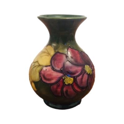 Moorcroft hibiscus vase with purple and red flowers on green. Paper label to the base W Moorcroft by appointment to the late Queen Mary. Main photo showing vase from an eye level angle.