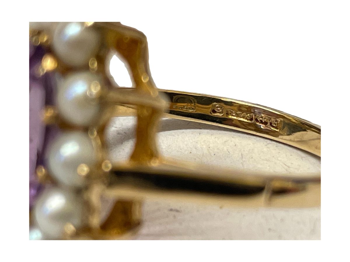 Antique style 9 karat gold ring set with a generously sized oval cut pale purple amethyst to the centre within a seed pearl frame. Full hallmark for Birmingham assay c1992. Ring size P / 7.5. Close up photo of the full hallmark to the inside band.