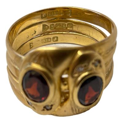 Art Deco double snake ring in 9 karat gold c1921. Each snake has an oval cut garnet to the top of their heads with small round cut diamonds for eyes. There is unusually a full hallmark on each of the 3 joined inner bands. Ring size V / 10.5. Photo of ring seen from the front and raised to show the full hallmark to each of the 3 bands at the back.