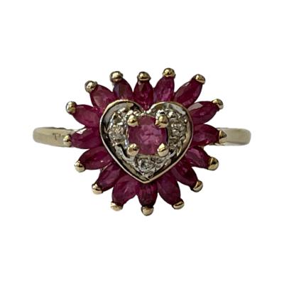 Modern 9 karat gold ring in the form of a heart. Round cut ruby to the centre with a white gold surround housing 3 small diamonds and an outer border of marquise cut rubies. The lowest ruby is a slightly darker shade. Ring size P / 7.5 Main photo of ring front showing the heart shaped design.