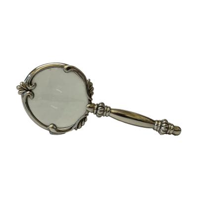 Small sterling silver magnifying glass. Pretty little magnifying glass in a sterling silver setting. Good magnification strength. Hallmark to tip of handle for 925 London import. The glass area measures approximately 52mm in diameter. Main photo of magnifying glass displayed sideways with glass end raised to th4e right.