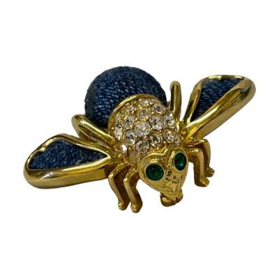 Vintage bee brooch from the Joan Rivers collection. Solidly made gilt metal brooch with denim blue wool wings and abdomen, clear rhinestone studded thorax and green rhinestone eyes. Signed to the back. In very good condition. No original box. Main photo of brooch seen with bee facing bottom right of photo, wings pointed bottom left and top right. The green rhinestone eyes clearly shown.