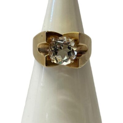 Vintage 9 karat gold and aquamarine ring. Modernist 9 karat gold ring set with an almost clear round cut aquamarine. Hallmarked for Birmingham assay c1975. Ring size L.5 / 6. Main photo of ring on a cone shaped display stand and seen from the front.