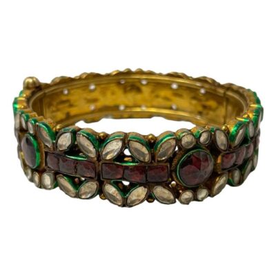 Vintage Indian polki style bracelet. Strikingly colourful bracelet in gilt silver with polki style smooth clear and faceted ruby glass. Each glass gem is hi-lighted with metallic bright green enamel. A beautiful bracelet which evokes the dreamy days of summer. Screw open/close clasp. Inside measurement of bracelet is 57mm and outer measures 68mm. Main photo of bracelet seen from an almost eye level angle with clasp closed and to the left.