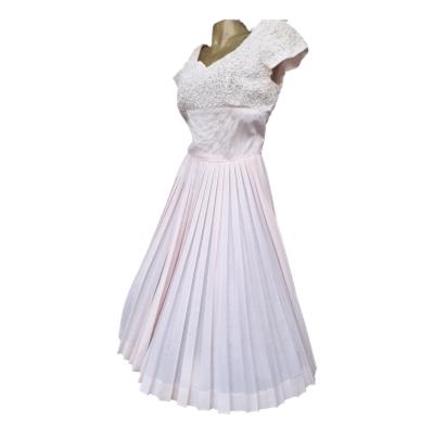 1950s pale pink dress with pleated full skirt. Sweetheart neckline with white braid and diamanté. Calf length. In good condition no marks etc. Being a 50s shape needs a fuller figure, larger bust so best for a size 14 with slim waistline. Main photo of dress shown slightly at a side angle with dress front facing off to the left.