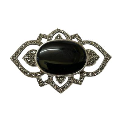 Art Deco style silver and onyx brooch. Timeless geometric Deco design brooch in sterling silver with a large black onyx cabochon to the centre and framed with an intricate marcasite surround. Hallmarked 925 to the back. All marcasite present. The onyx cabochon measures 26mm by 18mm. Main photo of brooch shown front facing with onyx positioned in a horizontally long position.