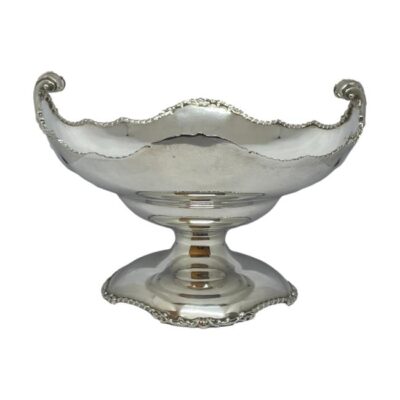 George V sterling silver tazza. Substantial sterling silver tazza by Mappin & Webb. Elegant design featuring twist pattern edging around the base and bowl with fleurs de lis style scrollwork handles. Full hallmark to outside of bowl for London assay c1932 and full Mappin and Webb stamp to the base. Base measures 146mm in diameter. 25 Troy ounces. COLLECT FROM STORE ONLY. Main photo of tazza from a near eye level angle with the fleurs-de-lis handles to the left and to the right.