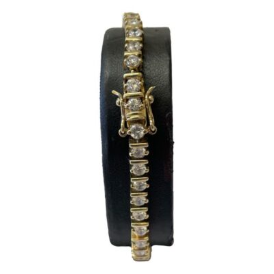 Modern gilt silver tennis bracelet. A sparkling tennis bracelet in gilt sterling silver with round cut cubic zirconia stones along the whole length. 2 hook fasteners to keep bracelet closed securely. Hallmarked 925 for sterling silver. Main photo of bracelet wrapped around a black display stand with the clasp area to the foreground.