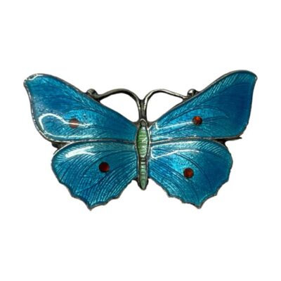 Antique sterling silver and enamel butterfly brooch. Stunning butterfly brooch with turquoise blue enamel wings with red dots and a pale lime green abdomen. Hallmarked sterling silver across the top of wings at the back and makers stamp for John Atkins & Sons and number 1087 on back of lower wings. c1910. Main photo of brooch in full with light bouncing off the vibrant colours of the enamel.