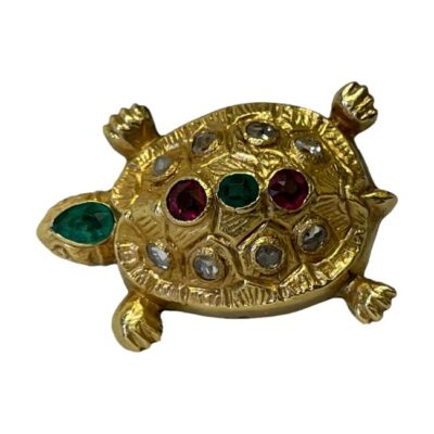 Antique tortoise brooch in unmarked gold. A beautifully crafted 19th century gold tortoise brooch with emeralds, old cut diamonds, ruby and red spinel. Main photo looking straight down at brooch from above. The tortoises head is to the left with largest gem stone of emerald to the top. On the shell, there is a line of red spinel, emerald and ruby with 4 old cut diamonds on either side of these.