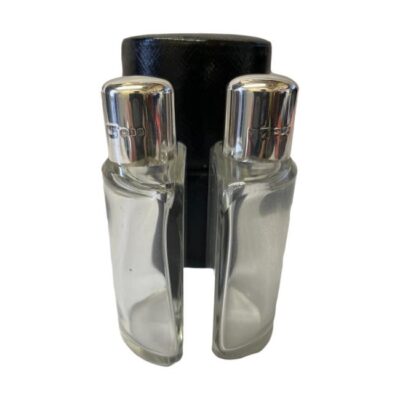 Art Deco silver topped cased bottles. A very practical cased set of 2 small half bottles with silver tops. Each bottle has sterling silver screw tops with original glass stoppers and own slot to keep secure within the case when in transit. Most likely used for cologne. Each bottle measures 53mm wide, 27mm deep at middle and 90mm tall. Full hallmark to each silver top for London assay c1926. Main photo of the 2 glass bottles displayed outside and in front of the leather case. The glass stoppers and silver screw tops are in place.